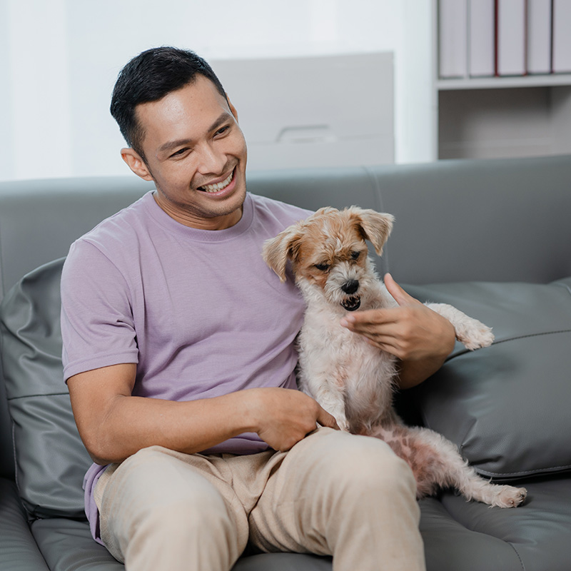 man sitting on a sofa smiling with a dog