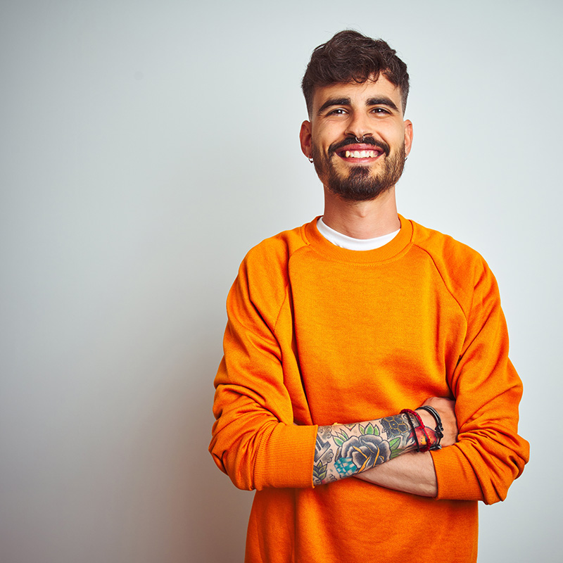 A smiling man with tattoos wearing a sweatshirt